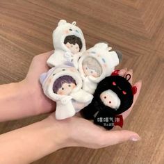 a hand holding three small figurines in the shape of people wearing polar bears