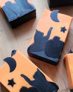 several pieces of chocolate with black and orange icing on them sitting on a wooden surface