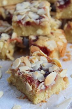 several pieces of cake sitting on top of paper with almonds and cranberries