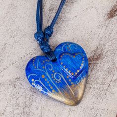 A heart as blue as the ocean comes to life in papier mache. Hand-painted motifs suggest the movement of the wind. Resplendent with golden accents the pendant centers a delightful necklace by Edith Orozco. A coat of lacquer protects it and adds shine. Blue Heart Necklace, Mexico Gift, Rattan Handbags, Skull Pendant Necklace, Skull Pendant, Black Skulls, Cool Necklaces, Blue Heart, Big Heart