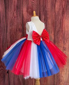 Your child can feel like a star! In her knee length red, white and blue tulle dress!  Bodice is made of white satin followed by a sowed in sash, followed by a deep V-Back with a hidden zipper. The big bow is detachable. The skirt consists of 3 multiple colored vertical tulle layers followed by two layers of soft white lining with crinoline to give it a fuller look. This specific dress is meant to be knee length, the size chart is located in the image section, it will be the last image and the measurements are in inches. Dress Is Pictured with a petticoat NOT INCLUDED https://www.etsy.com/listing/1316417982/white-knee-length-petticoat-wedding?click_key=41cb8b0ae4587efa582b0a433f3f5e0cde12aec0%3A1316417982&click_sum=af1df37b&ref=shop_home_active_1 Visit our store, more items to come!  https: White Sleeveless Princess Dress For Christmas, White Tulle Christmas Dress, White Sleeveless Princess Dress For Holidays, Summer Red Tutu Dress For Dress-up, Red Summer Tutu Dress Costume, Red Tulle Princess Dress For Summer, Summer Red Tulle Princess Dress, Red Tulle Summer Princess Dress, Holiday White Princess Tutu Dress