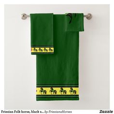 two green towels with horses on them hanging from a towel rack in front of a white wall