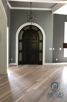 an empty living room with wood floors and gray walls is seen in this image from the entryway