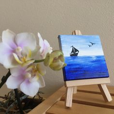 a small easel with a painting on it next to a flower