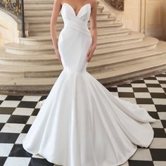 a woman in a white wedding dress standing on a black and white checkered floor