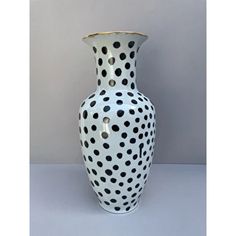 a black and white vase with polka dots on the bottom is sitting against a gray background