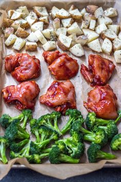 chicken, broccoli and potatoes are arranged on a baking sheet with parchment paper