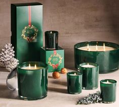 green candles are sitting next to each other in front of a box and pine cones