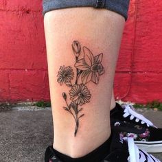 a woman's lower leg with flowers on it and a red brick wall in the background