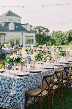 a long table with blue and white cloths is set up in front of a large house