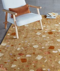 a chair sitting on top of a rug next to a white chair and a table