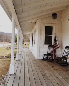 two rocking chairs on the front porch of a white house