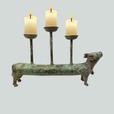 three candles are lit in the shape of a dog on a stand with two dogs