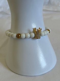 White and Gold beaded charm bracelet with queen crown accent Elegant Charm Bracelet With Letter And Round Beads, Elegant White Round Beads Charm Bracelet, Elegant White Charm Bracelet With Round Beads, Elegant White Charm Bracelet, Elegant White Bracelets With Charms, White Crown Design Jewelry Gift, White Crown Design Jewelry As Gift, Elegant White Charm Bracelet With 8mm Beads, White Beaded Charms Bracelets