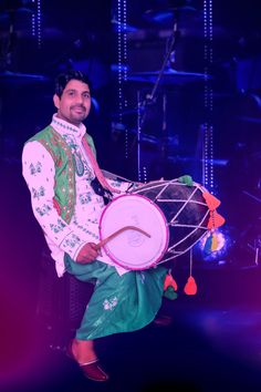 a man is holding a large drum on stage