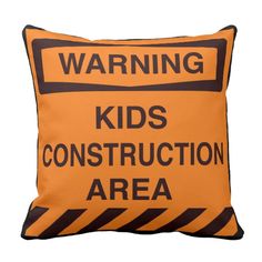 a pillow that says warning kids construction area on an orange and black striped pillow cover