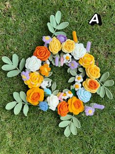 a wreath made out of crochet flowers and leaves on grass with the number 4 in the middle