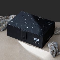 a black box with white sprinkles on it next to rocks and a rock