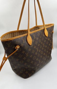 The Neverfull MM tote unites timeless design with heritage details. Made from supple Monogram canvas with natural cowhide trim, it is roomy yet not bulky, with side laces that cinch for a sleek allure or loosen for a casual look. Slim, comfortable handles slip easily over the shoulder or arm. The Louis Vuitton monogram is a print that is carefully crafted from durable, brown canvas, Louis Vuitton's embossed, classic interwoven "LV" has remained the brand's signature since 1896. Louis Vuitton’s coated canvas is one of the most durable materials in the game. Originally created for use on the brand’s travel trunks. The material’s durability shouldn’t come as much of a surprise, considering the travel trunks back in the day needed to withstand a lot of wear and tear. It’s not only resistant to Louise Vuitton, Louis Vuitton Neverfull Pm, Louis Vuitton Dust Bag, Louis Vuitton Totes, Louis Vuitton Neverfull Mm, Neverfull Mm, Vuitton Neverfull, Brown Canvas, Lv Bag