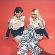 two people sitting on the ground wearing matching clothing