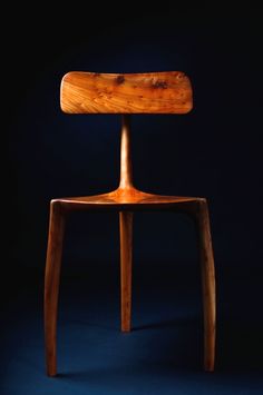 a wooden chair sitting on top of a blue floor next to a black wall in the dark