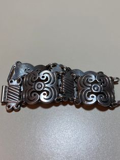 "This is a stunning, vintage, handmade Taxco sterling silver bracelet that has a beautiful, ornate Art Nouveau feel to it. The bracelet is about 8 inches. It is very hard to find these gorgeous Taxco bracelets in larger sizes like this one. It is very well-made and is about 1 1/8\" in width. It has an older style sterling silver hook clasp. The bracelet weighs a hefty 73.6 grams. It is stamped Mexico 925 with a faded Taxco hallmark/logo. Very pretty and well-made. See pictures for details. More Collectible Sterling Silver Antique Bracelet, Antique Hallmarked Sterling Silver Bracelet, Vintage Oxidized Antique Silver Bracelet, Ornate Sterling Silver Bracelet With Oxidized Finish As Gift, Vintage Handmade Sterling Silver Bracelet In Antique Silver, Handmade Vintage Sterling Silver Bracelets, Ornate Hallmarked Sterling Silver Bracelet For Anniversary, Ornate Sterling Silver Anniversary Bracelet, Vintage Silver Bracelet With Oxidized Finish