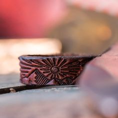 a wooden ring sitting on top of a table next to a piece of wood with an intricate design