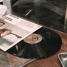 an old record player is playing music on the table next to a glass case with a sheet of paper in front of it