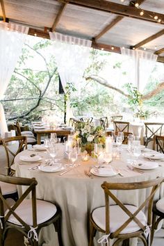 the table is set with white linens and place settings for guests to sit at