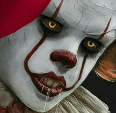 a close up of a clown's face with yellow eyes and red hat on