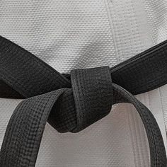 a black belt on the back of a white uniform with grey and black stripes around it