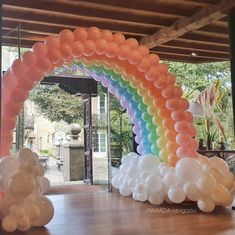 an arch made out of balloons in front of a doorway that has a rainbow on it