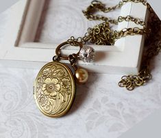 FlowerAntique Gold Locket Necklace - Floral Locket - Oval Locket Photo Flower - Art Nouveau - Rhinestone Pearl - Vintage Boho Chic - Mom Gift for Her . . . This fabulous Art Nouveau antique gold locket features an inlaid bouquet of flowers. The front side of this oval locket is beautifully engraved, the antique finish adds depth and contrast to the lovely floral and vine design. This is one of my favorite lockets! Grand Millennium Style. This beautiful flower designed antique gold locket is ador Gold Flower Necklace With Vintage Charm, Bronze Locket Necklace With Vintage Charm For Wedding, Elegant Bronze Locket Necklace For Wedding, Vintage Gold Flower Necklace, Antique Gold Flower Jewelry, Wedding Brass Jewelry With Flower Charm, Wedding Jewelry With Flower Charm In Brass, Vintage Brass Jewelry With Flower Charm, Vintage Gold Jewelry With Flower Charm