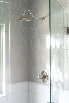 a bathroom with a glass shower door and white tile on the walls, along with a toilet