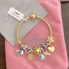 a bracelet with charms on it sitting on top of a pink napkin