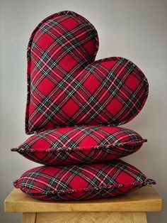 three pillows stacked on top of each other in the shape of a heart, sitting on a wooden table