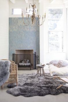 a living room filled with furniture and a chandelier hanging from the ceiling over a fire place