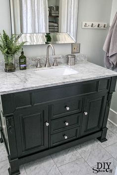 a bathroom with marble counter tops and black cabinets