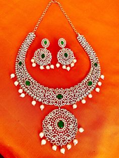 This stunning CZ American Diamond South Indian Haaram is a perfect addition to your collection. Featuring green stones and a medium size, it is ideal for both weddings and parties. It also makes a great gift for her. Elevate your Indian outfit, whether it's a silk saree or a gown, with this elegant piece. This jewellery set includes a necklace, matching earrings. Jewellery Care- Keep the jewellery dry, avoid contact with perfumes and water. Green Bridal Necklace With Stone Work, Formal Green Bridal Necklace With Sparkling Stones, Green Emerald Bridal Necklace For Party, Green Stone Work Bridal Necklace For Gift, Green Stone Work Bridal Necklace, Green Bridal Necklace With Stone Work As Gift, Green Bridal Necklace With Stone Work For Gift, Green Bridal Necklace With Stone Work For Celebration, Green Diamond Bridal Necklace For Party