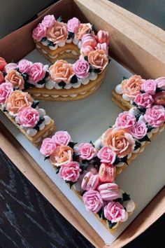 a heart shaped cake with pink flowers on top in a cardboard box, ready to be eaten