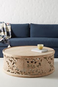 a living room with a blue couch and coffee table in front of a white wall