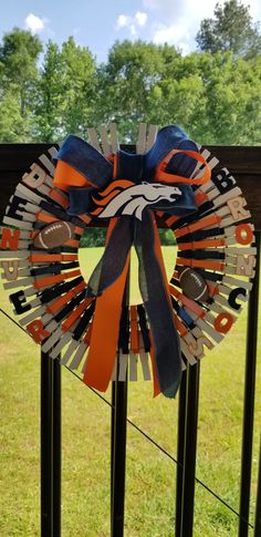 an orange, white and blue football ribbon on a gate with trees in the background