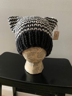 a black and white knitted hat on top of a wooden head mannequin