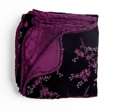 the purple and black blanket is folded on top of each other