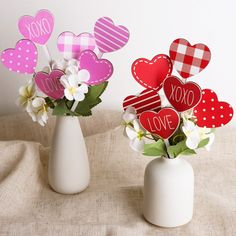 two vases filled with flowers and paper hearts