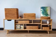 a wooden shelf with baskets on top of it next to a painting and other items