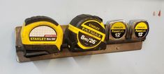 three yellow and black tape measures are on a metal holder with magnets attached to it