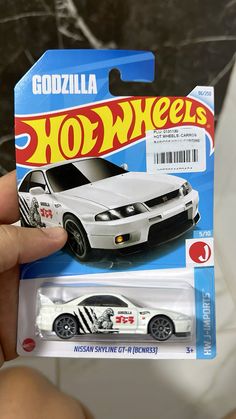 a hand holding a white toy car in it's package