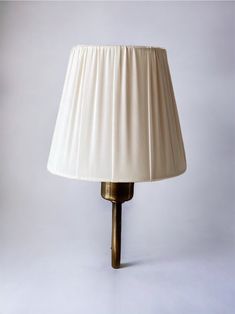 a lamp that is on top of a white surface with a light shade over it