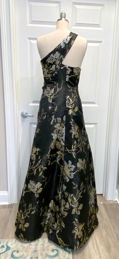 a black and gold dress on a mannequin in front of a white door